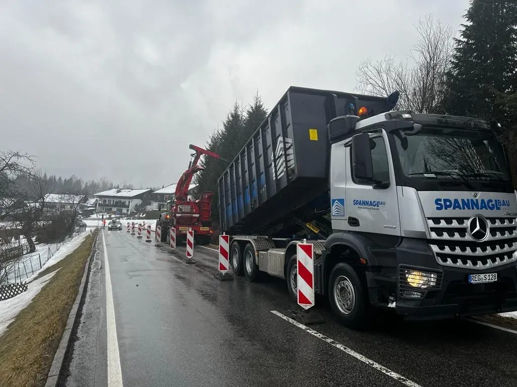 Abrollkipper von Spannagl Bau an einer abgesperrten Straßenbaustelle im Winter